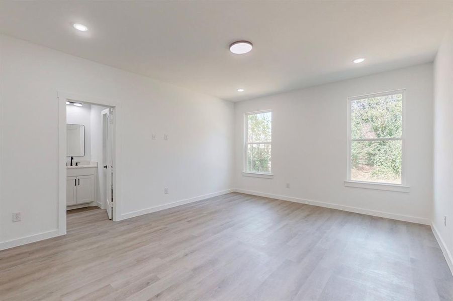 Unfurnished room featuring light wood-type flooring, sink, and a healthy amount of sunlight