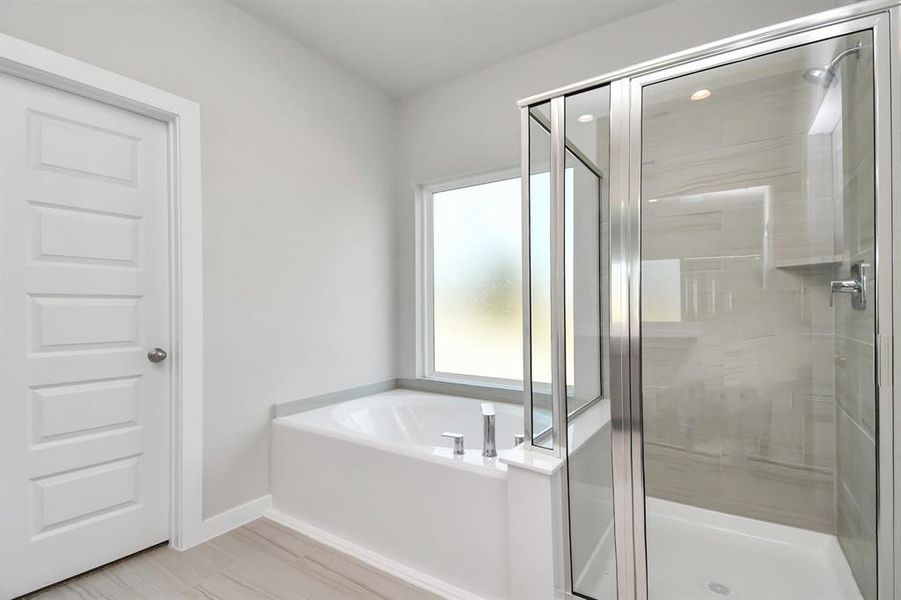 Enjoy a walk-in shower with tile surround, a separate garden tub with custom detailing. Sample photo of completed home with similar floor plan. Actual colors and selections may vary.