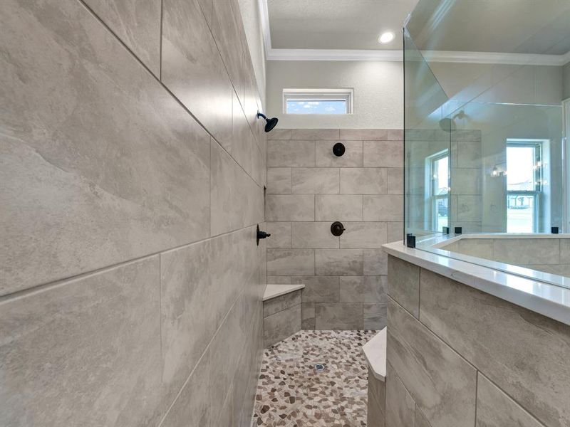 Bathroom with tile walls, a wealth of natural light, a tile shower, and crown molding