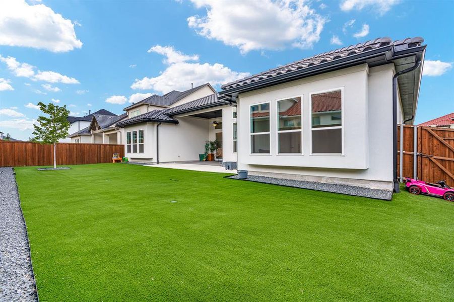 Back of property featuring a expanded patio area and a beautiful artificial turf