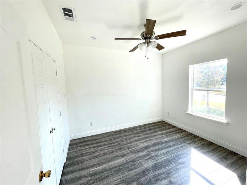 Empty room featuring dark wood-type flooring and ceiling fan