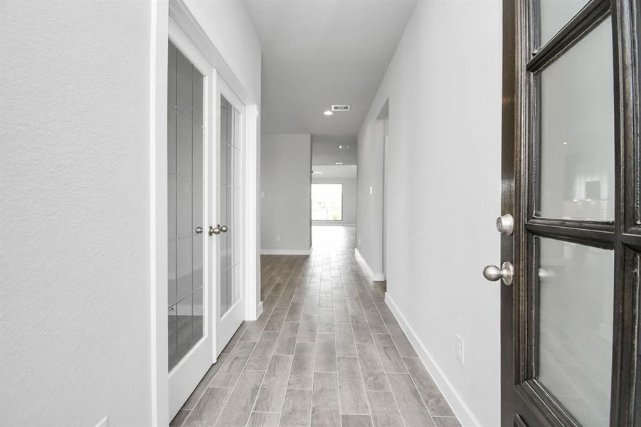 The majestic entryway allures with its high ceilings, embellished with sophisticated wood-look tile flooring and sleek oversized baseboards. Sample photo of completed home with similar floor plan. Actual colors and selections may vary.