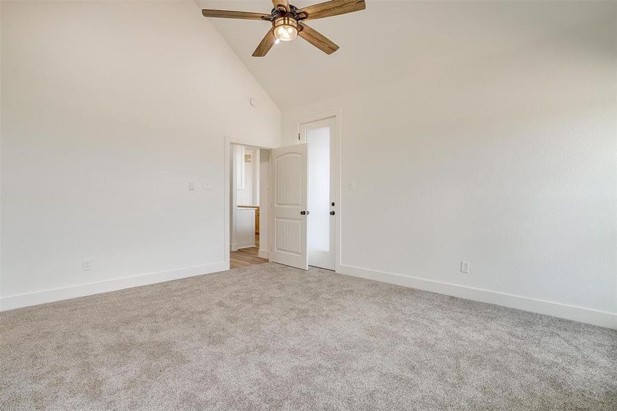 Carpeted empty room featuring high vaulted ceiling and ceiling fan