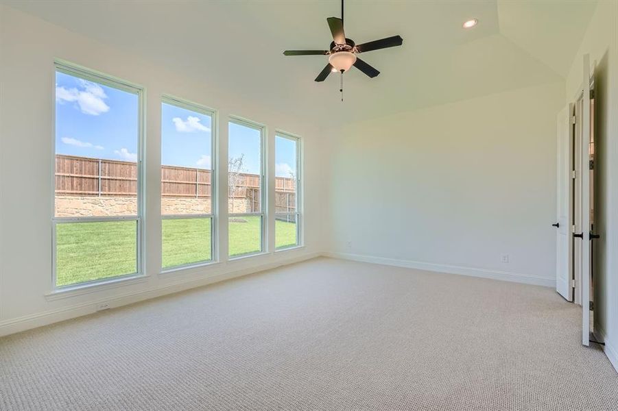 Unfurnished room featuring light carpet, vaulted ceiling, and ceiling fan