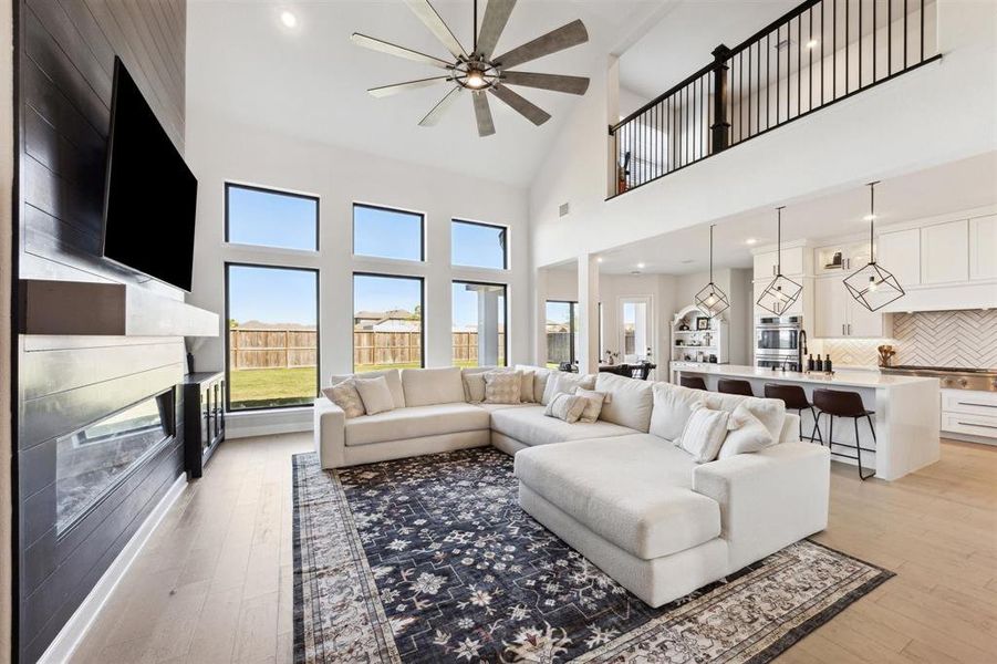 The spacious open-plan living area boasts high ceilings, large windows for ample natural light, an elegant fireplace, and a seamless transition to a well-equipped kitchen with a breakfast bar.