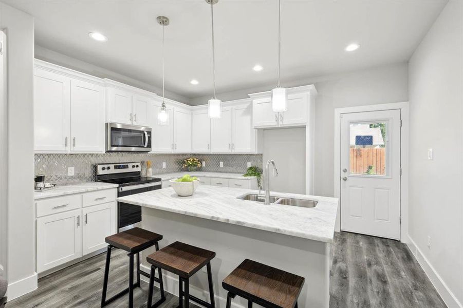 Kitchen featuring pendant lighting, white cabinets, sink, and appliances with stainless steel finishes