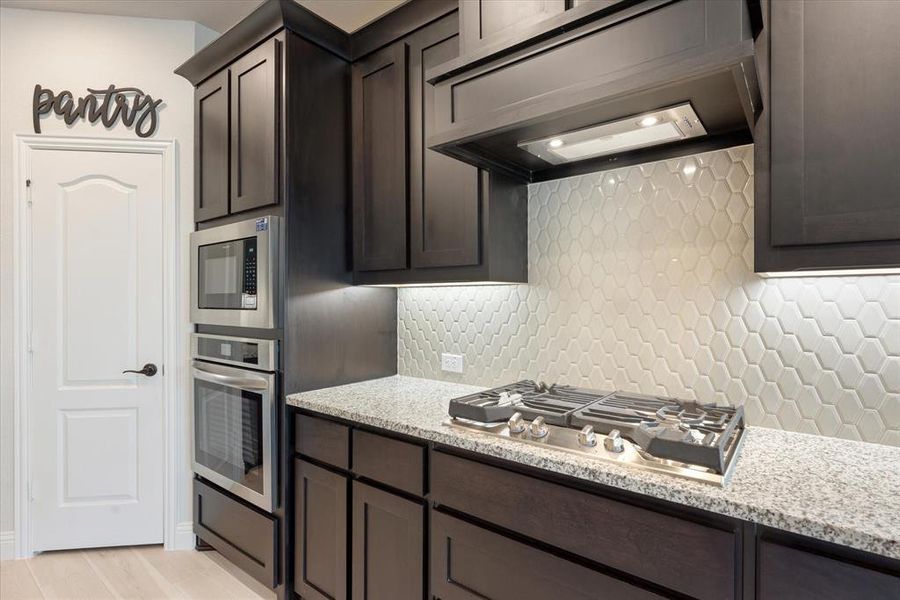 Kitchen has a tasteful white tile backsplash, gas cooktop and wood surround exhaust hood. The oven is convection for best baking results. The pantry is a walk in for ample storage space.