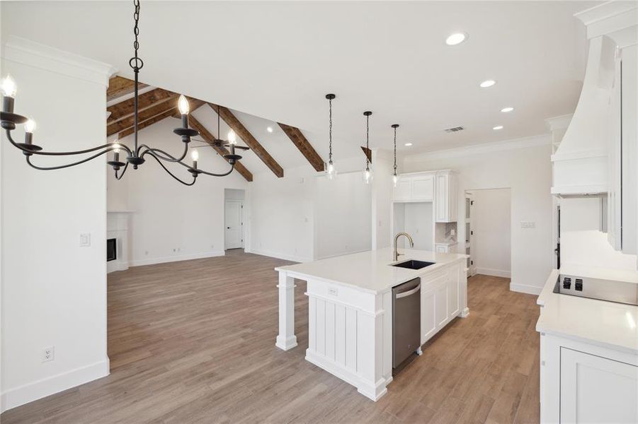 Kitchen featuring a center island with sink, white cabinetry, sink, and light wood-type flooring