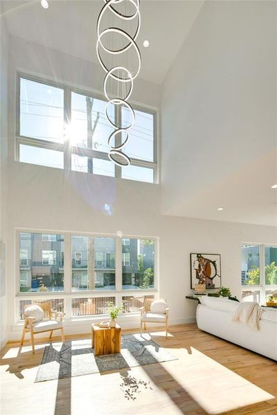 Living room featuring light hardwood / wood-style floors, a notable chandelier, and high vaulted ceiling