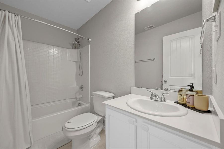 Full bathroom featuring shower / bathtub combination with curtain, toilet, and vanity