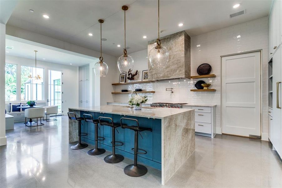 Kitchen featuring decorative backsplash, white cabinets, custom exhaust hood, and decorative light fixtures