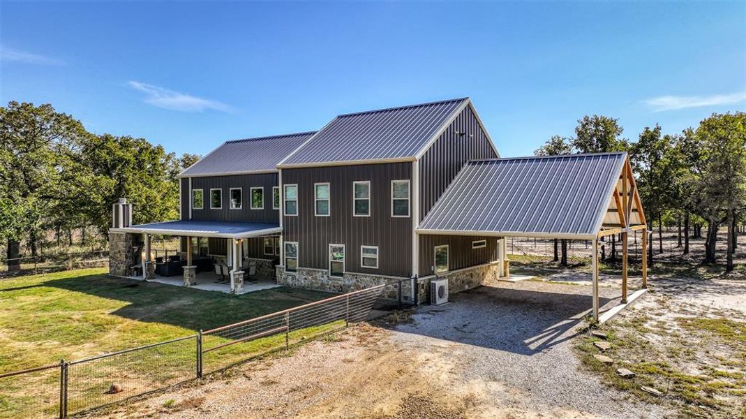 The back of the home features a massive porch, complete with a charming stone fireplace, perfect for outdoor gatherings and enjoying the surrounding landscape.