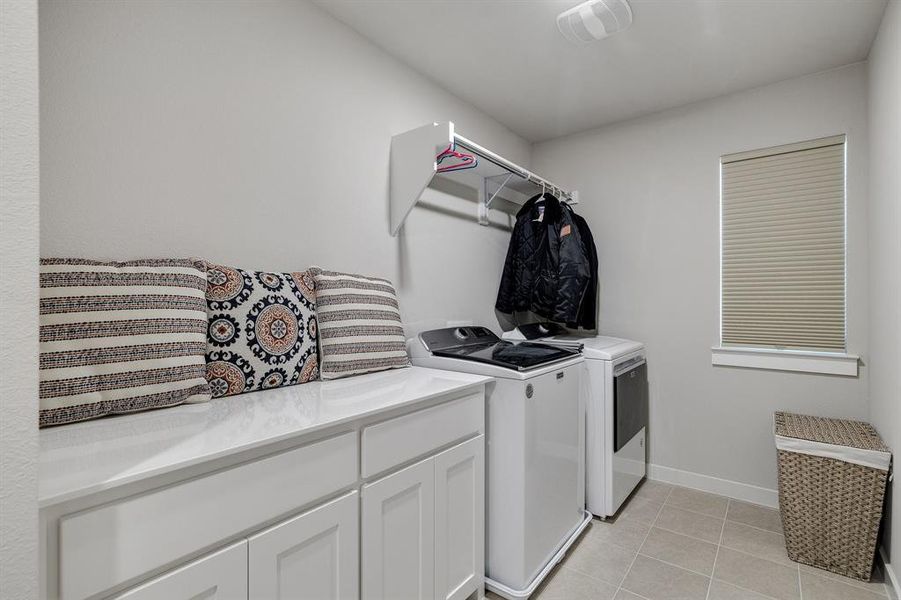 Clothes washing area featuring light tile patterned floors, separate washer and dryer, and cabinets