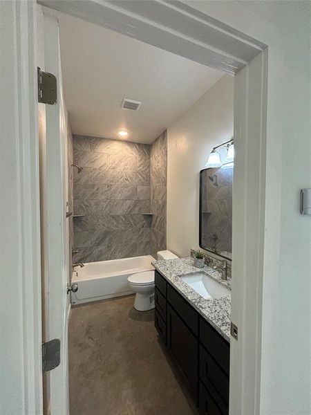 Full bathroom with vanity, toilet, concrete floors, and tiled shower / bath