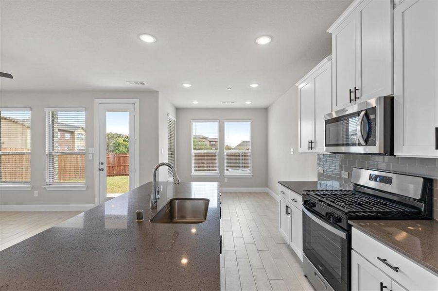 Kitchen featuring dark stone countertops, white cabinetry, sink, appliances with stainless steel finishes, and light hardwood / wood-style floors