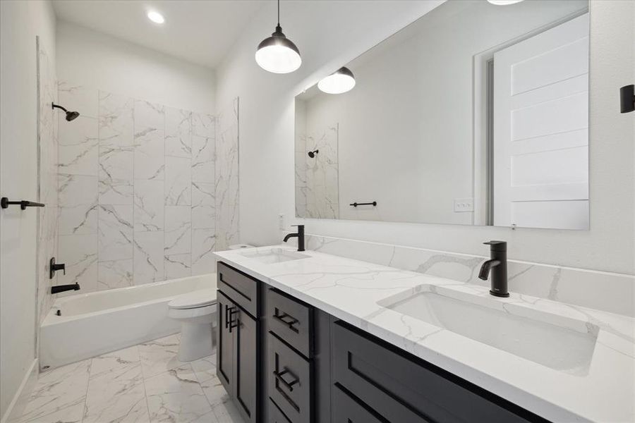 Secondary bathroom features dark cabinets, tile floors, dual sinks, and a tub and shower combo with tile surround.