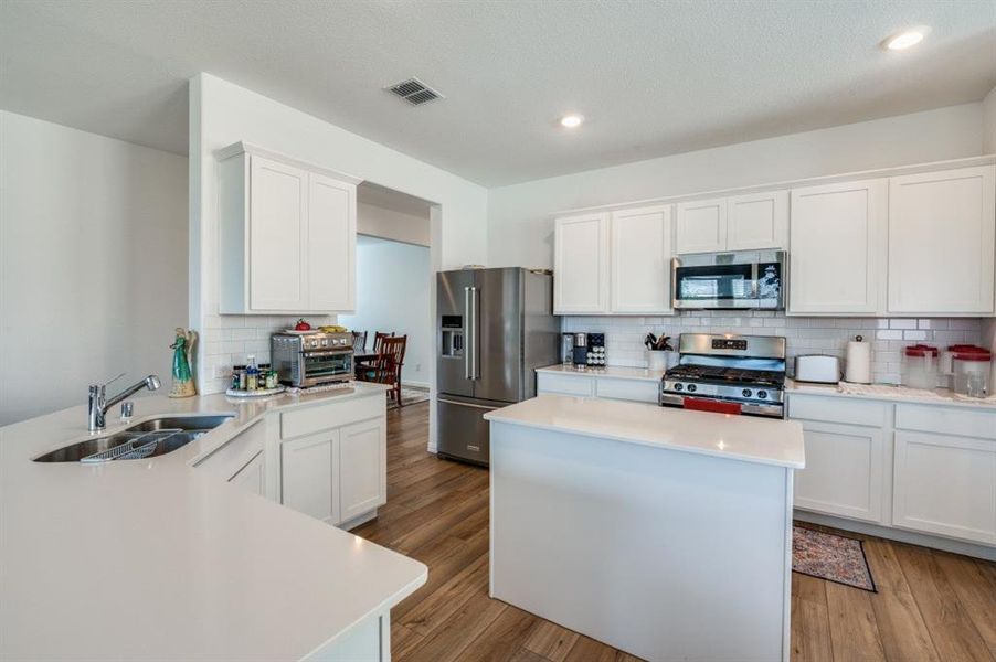 Kitchen with appliances with stainless steel finishes, light hardwood / wood-style floors, and white cabinetry