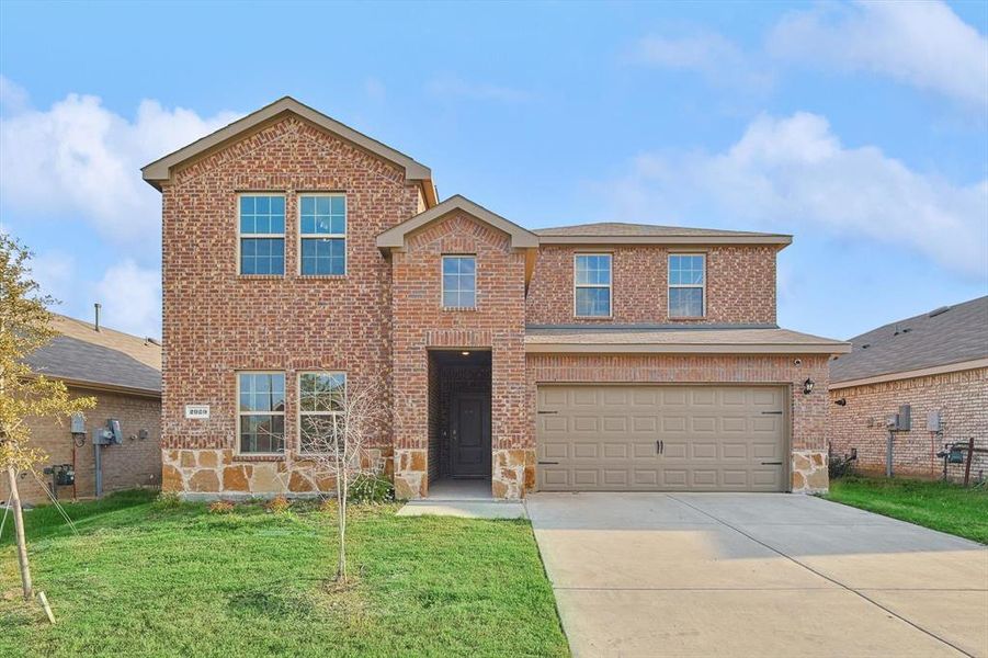 View of front property featuring a garage and a front lawn