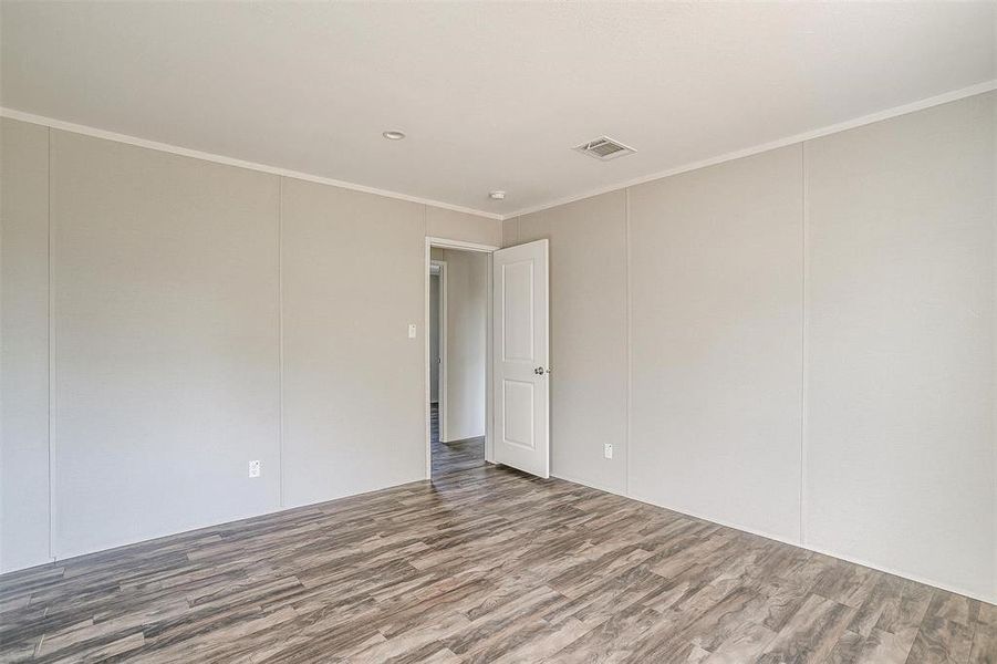 Empty room featuring ornamental molding and wood-type flooring