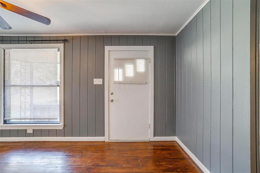 Foyer entrance featuring dark wood-type flooring, a healthy amount of sunlight, ornamental molding, and wooden walls