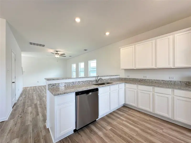 Kitchen includes granite countertops, luxury vinyl plank flooring, 36” upper cabinets with crown molding, a full suite of stainless-steel Whirlpool appliances – including refrigerator with ice maker, recessed lighting, and a large single basin sink.