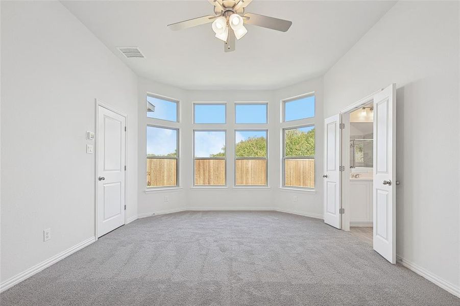 Carpeted spare room with plenty of natural light and ceiling fan