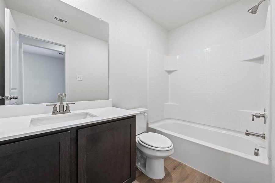 Full bathroom featuring wood-style flooring, washtub / shower combination, vanity, and toilet