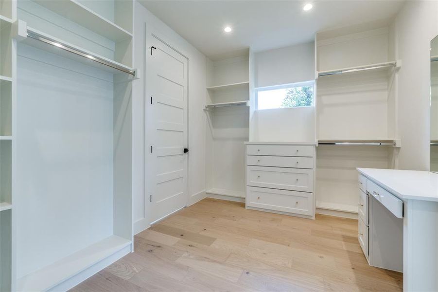 spacious primary closet with built-ins, including makeup vanity