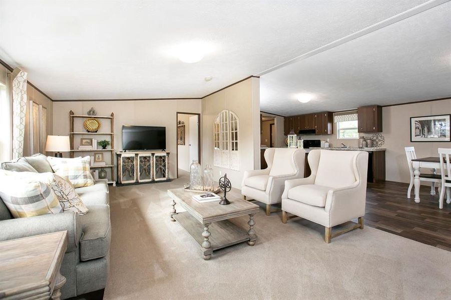 Living room featuring light hardwood / wood-style flooring, vaulted ceiling, a textured ceiling, and ornamental molding