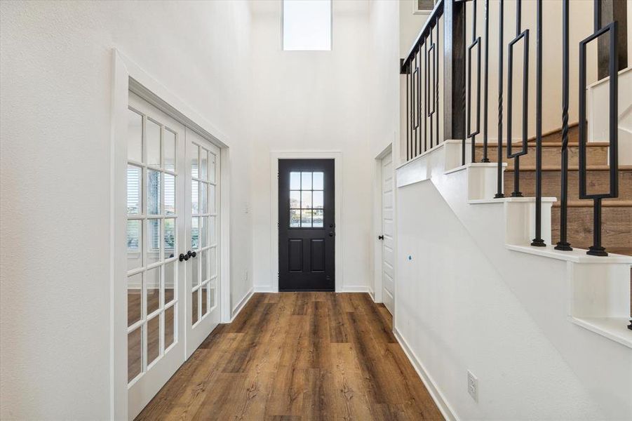 Step inside to a bright and airy entryway featuring sleek wood floors and an abundance of natural light. The open staircase and double glass doors leading to a flex room create a welcoming first impression. This space sets the tone for the modern elegance found throughout the home, offering a glimpse into the spacious and thoughtfully designed interiors.