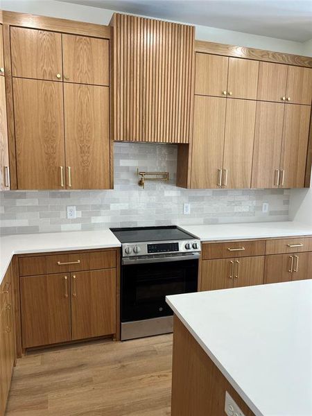 Kitchen featuring tasteful backsplash, electric stove, and light wood-type flooring