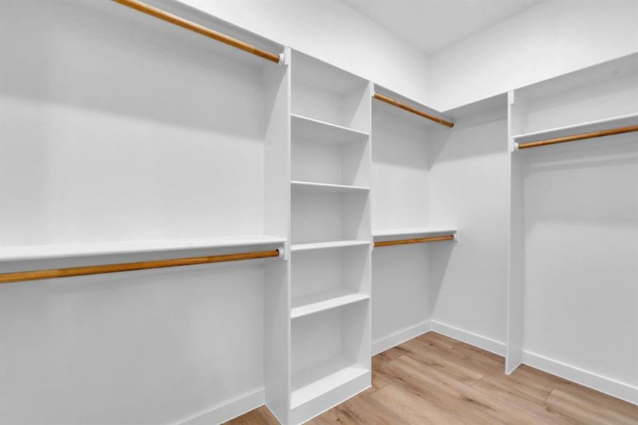 Walk in closet with light hardwood / wood-style floors