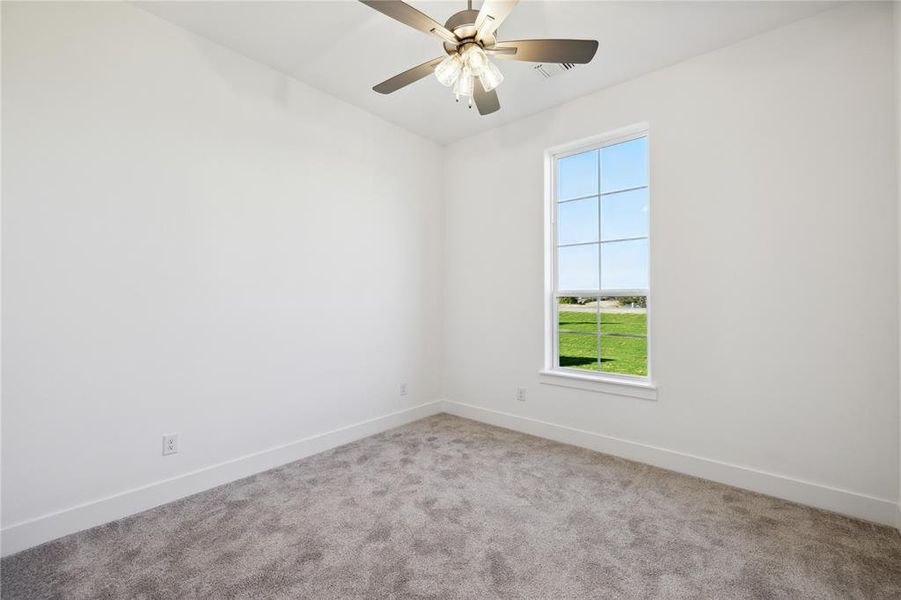 Carpeted spare room featuring ceiling fan