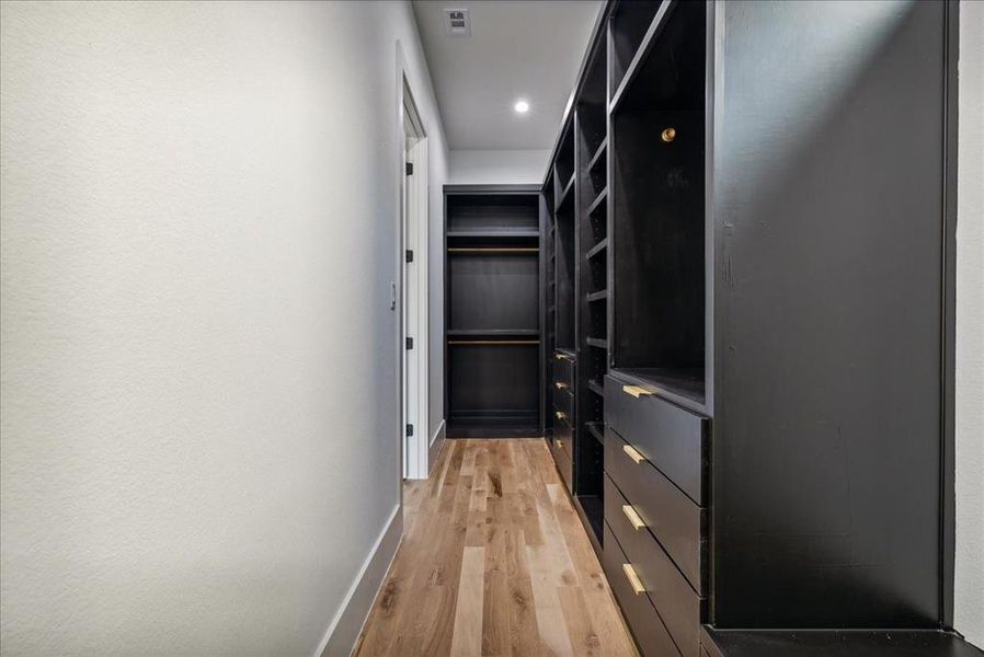 Walk in closet with hardwood / wood-style flooring