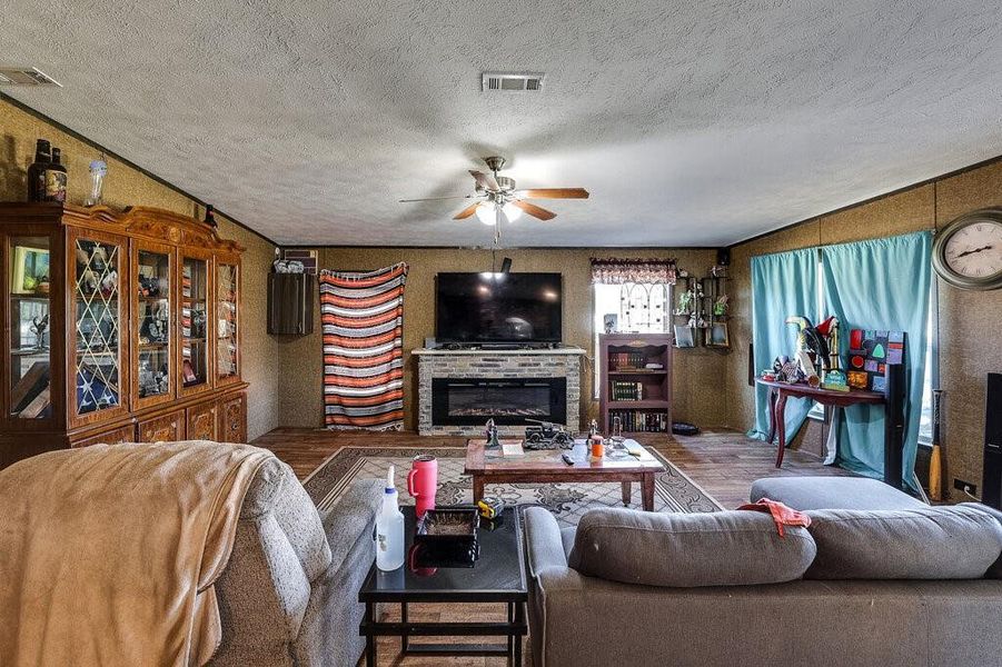 Living room with a textured ceiling, hardwood / wood-style flooring, and ceiling fan