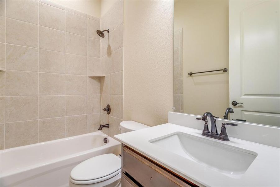 Full bathroom with tiled shower / bath combo, toilet, and vanity