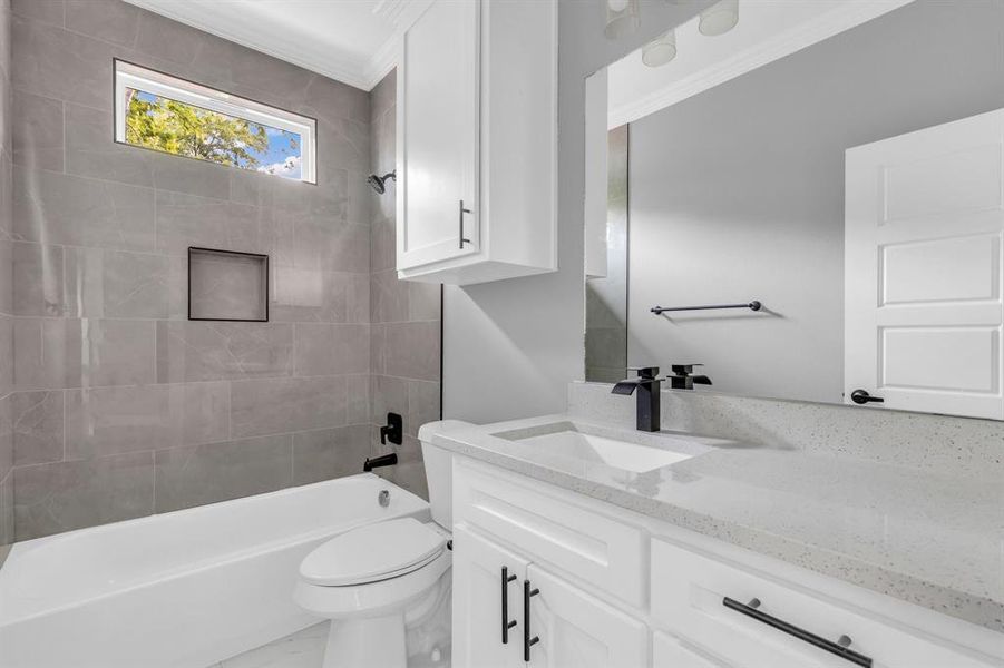 Full bathroom with crown molding, tiled shower / bath, vanity, and toilet