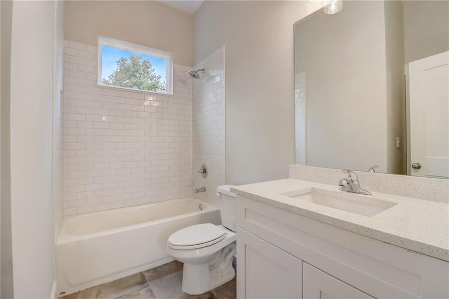Full bathroom featuring tiled shower / bath, oversized vanity, toilet, and tile floors