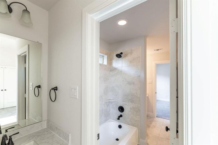 Bathroom with sink, tiled shower / bath, and tile patterned flooring