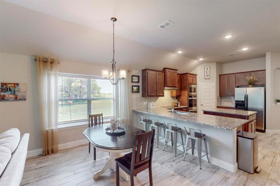 Kitchen with lofted ceiling, light hardwood / wood-style flooring, stainless steel appliances, decorative backsplash, and sink