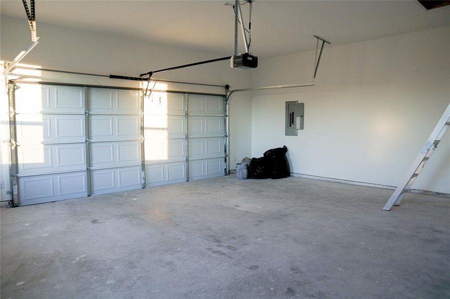 Garage featuring a garage door opener and electric panel