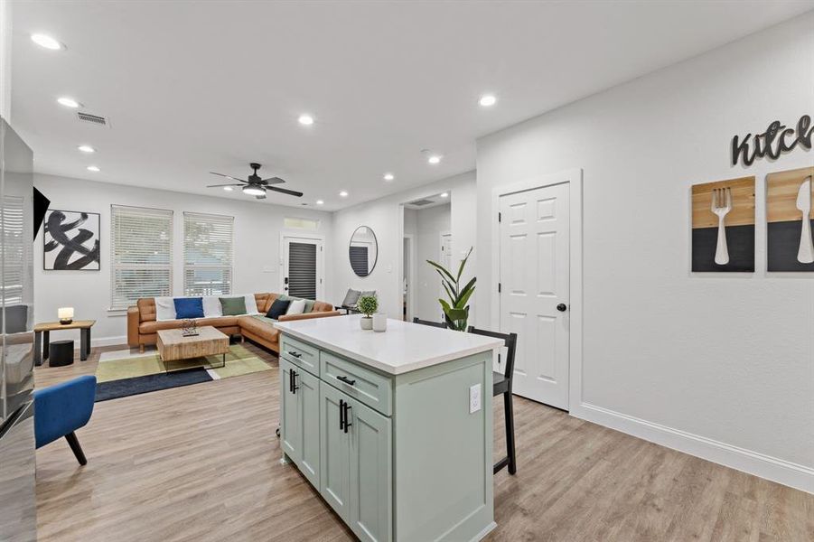 Kitchen with a kitchen breakfast bar, ceiling fan, light wood-type flooring, and a kitchen island