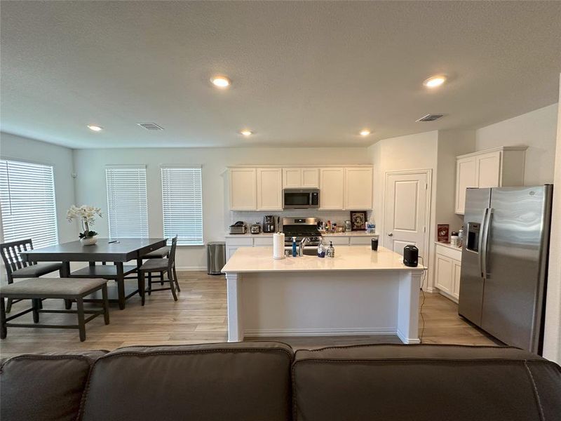 Kitchen with white cabinets, stainless steel appliances, and an island with sink