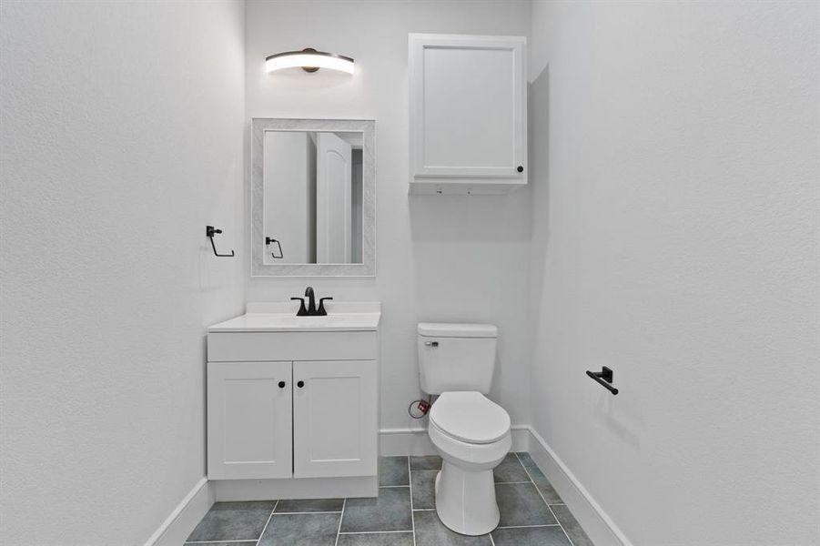 Bathroom featuring tile patterned flooring, toilet, and vanity