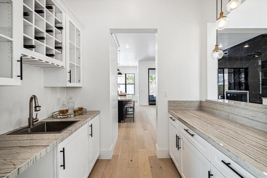 This stylish butler's pantry doubles as a wet bar, seamlessly opening up to the family room. Features storage, glass front cabinets, ideal for serving food and drinks