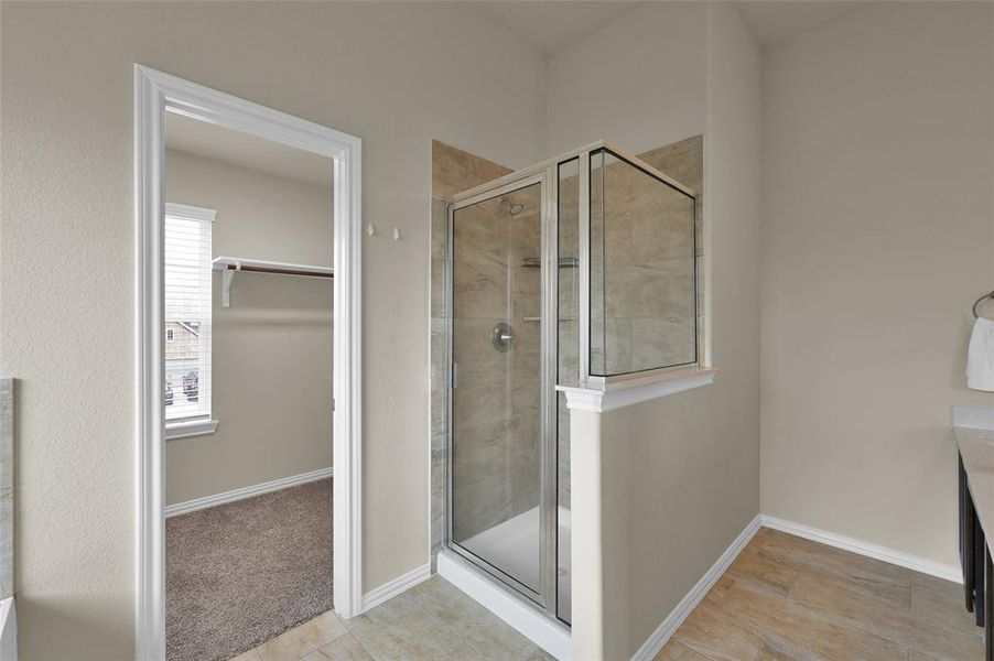 This is a modern bathroom featuring a glass-enclosed shower with tile walls, a built-in shelf, neutral colors, window for natural light.