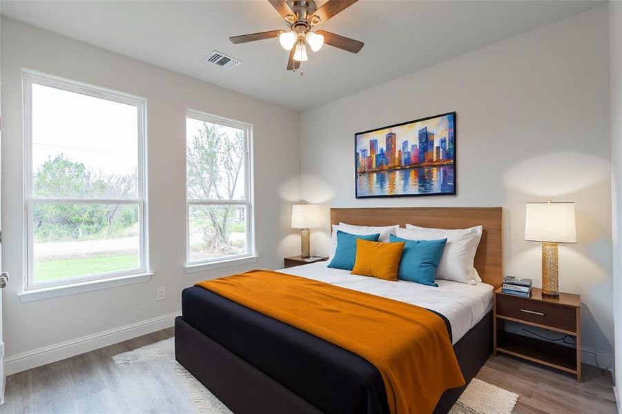 Bedroom with multiple windows, hardwood / wood-style flooring, and ceiling fan