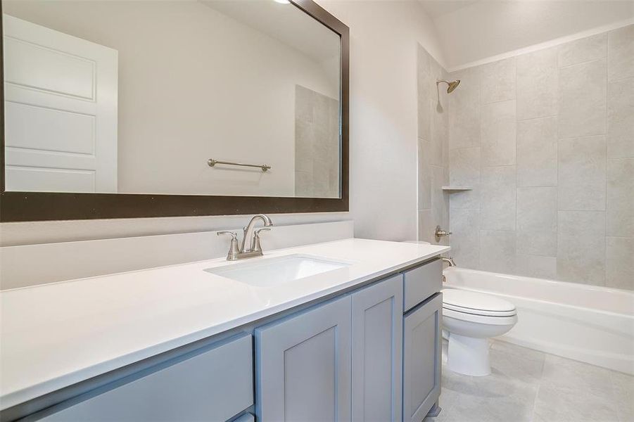 Full bathroom featuring tile patterned floors, vanity, tiled shower / bath, and toilet