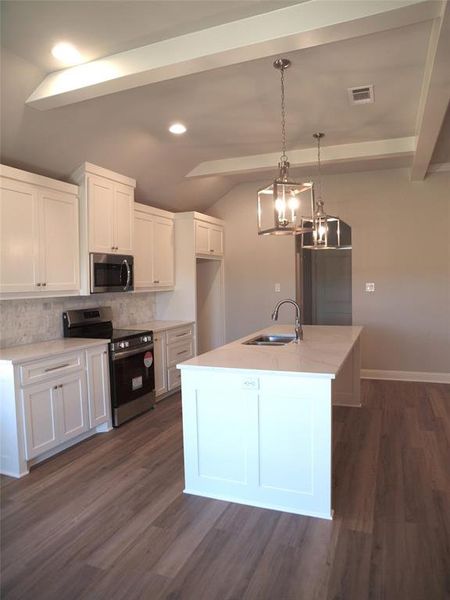 Kitchen with stainless steel appliances, white cabinets, dark wood-type flooring, and sink