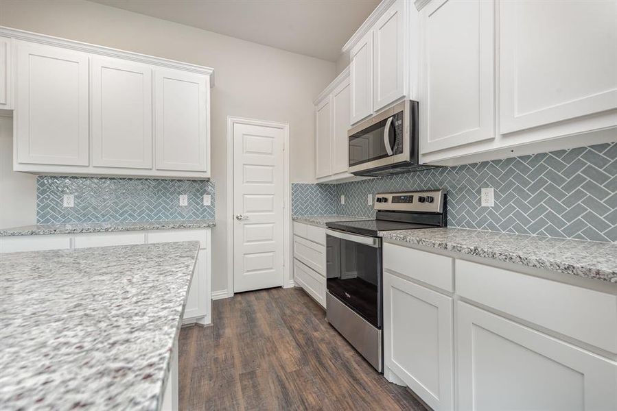 Kitchen featuring white cabinetry, tasteful backsplash, light stone counters, stainless steel appliances, and dark hardwood / wood-style floors